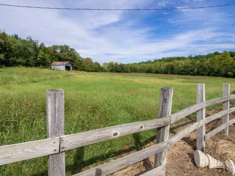 Weathered fence bordering an open property where a boundary survey may reveal differences from the recorded property line.