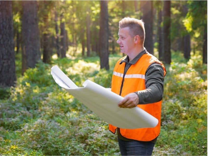 Surveyor reviewing property records and site plans in the field during a land surveying file update.